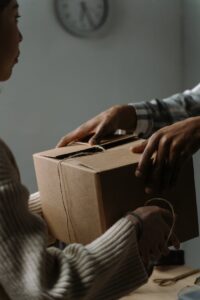 A close-up image featuring hands exchanging a cardboard box in an indoor setting.